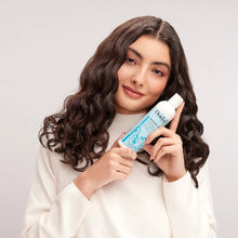 Cargar imagen en el visor de la galería, Modelo cargando botella de Acondicionador Ouidad Moisture Lock 250ml sin enjuague para rizos suaves.