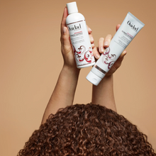 Cargar imagen en el visor de la galería, Modelo cargando Crema Ouidad Advanced Climate Control 168ml para controlar frizz y definir rizos.