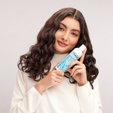 Cargar imagen en el visor de la galería, Modelo agarrando botella de Acondicionador profesional Ouidad Moisture Lock Leave-In 1L sin enjuague.