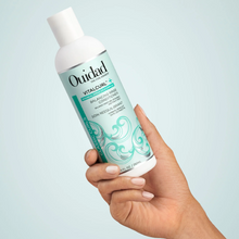 Cargar imagen en el visor de la galería, Mano cargando Botella Acondicionador Ouidad VitalCurl Plus Balancing Rinse 250ml para equilibrar e hidratar rizos.