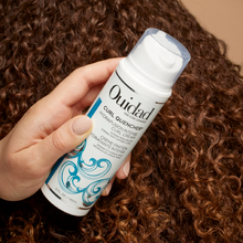 Cargar imagen en el visor de la galería, Mano agarrando Crema Ouidad Curl Quencher Hydrafusion 150ml para definir e hidratar rizos.
